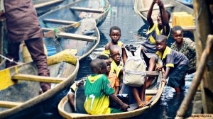 Photo of several children climbing into small wooden boat