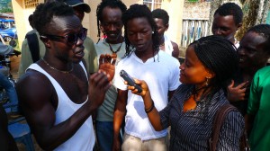Female journalist holds recorder while talking to group of men