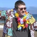 ein junger Mann mit Hawaiihemd und Kunstblüten-Kette tanzt Samba