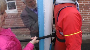 Ein Mann und eine Frau befestigen eine Spezialjacke mit Segel an Michael Wigge