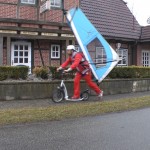 Michael Wigge auf seinem Tretroller mit Surfsegel auf dem Rücken