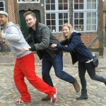 Michael Wigge, Steffen Thamm und Dietke Studemund in Tretroller-Pose vor einem Fachwerkhaus