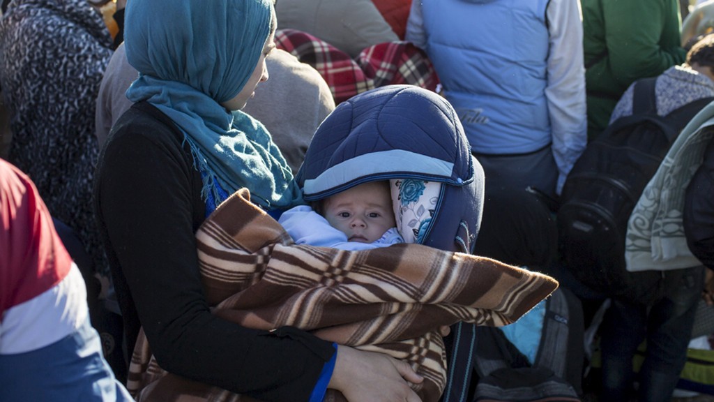 A migrant carries a child in a makeshift camp at a collection point in the village of Roszke, Hungary, September 7, 2015. @ Reuters/Marko Djurica